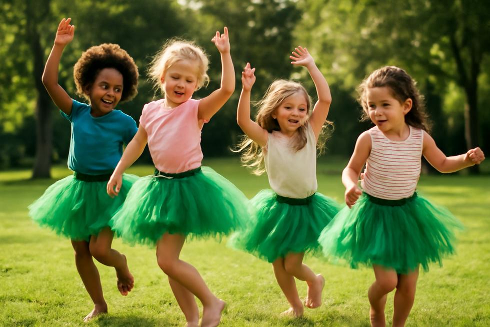 Happy children wearing green tutu skirts while dancing in a sunlit park.