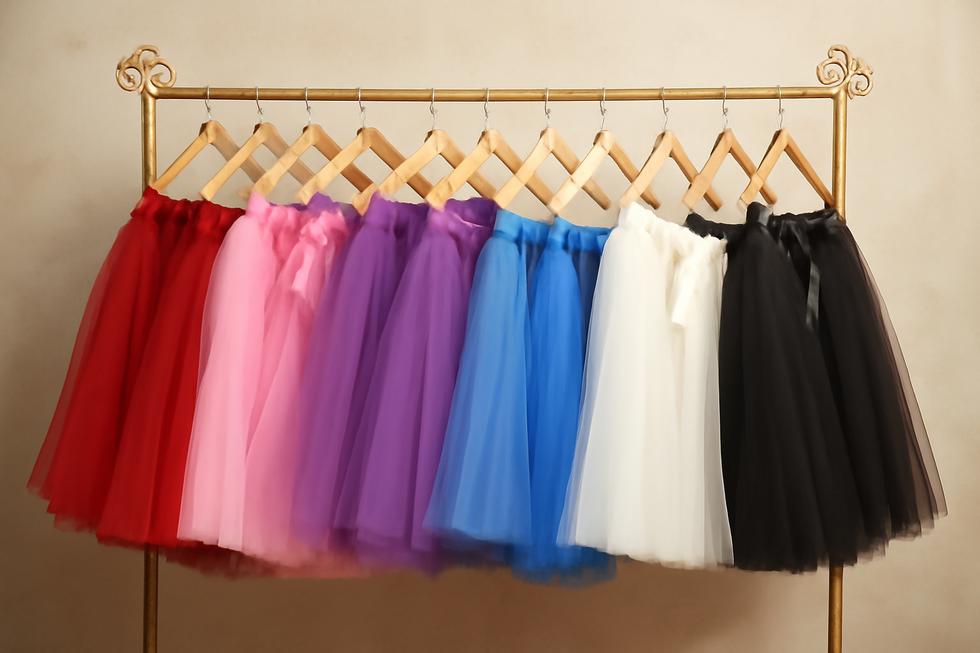 A vibrant collection of plus size tutus displayed on a rack, demonstrating diverse styles and colors.